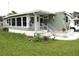 Side view of a single-wide mobile home showing a large covered porch and a small garden at 5448 Joy Ct, North Port, FL 34287