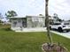 Front view of a green mobile home with a carport and well-maintained lawn at 5448 Joy Ct, North Port, FL 34287