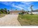 Tan house with 3-car garage, paver driveway, and landscaping at 594 Rotonda Cir, Rotonda West, FL 33947