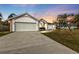 House exterior at sunset, featuring a two-car garage and manicured lawn at 87 Torrington St, Port Charlotte, FL 33954