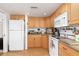 Bright kitchen featuring wood cabinets, granite countertops, and white appliances at 1801 Jamaica Way # 112, Punta Gorda, FL 33950