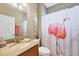 Bathroom with granite countertop vanity, flamingo shower curtain, and decorative nautical themed art at 25187 Keygrass Ct, Punta Gorda, FL 33955