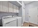 Well-lit laundry room featuring white cabinets, a modern washer and dryer, and neutral flooring at 25187 Keygrass Ct, Punta Gorda, FL 33955