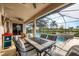Outdoor dining area on a screened patio, overlooking a pool, a spa, and lush landscaping at 25187 Keygrass Ct, Punta Gorda, FL 33955
