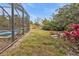 Landscaped backyard with pool enclosure and privacy fence at 3000 Narcissus Ter, North Port, FL 34286