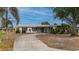 Ranch-style home with circular driveway, metal roof, and mature landscaping at 450 Capri Isles Ct, Punta Gorda, FL 33950