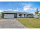 Newly renovated home with gray exterior, white garage door, and a spacious lawn at 745 Kellstadt Nw St, Port Charlotte, FL 33952
