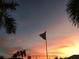 Scenic view of an American flag waving against a colorful sunset sky with palm tree silhouettes at 805 Brenda Ct, Punta Gorda, FL 33950
