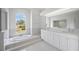 Elegant bathroom with double vanity, soaking tub, and large window at 8326 Creekview Ln, Englewood, FL 34224