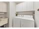 Bright laundry room with washer, dryer, cabinets, and utility sink at 10 Windward Ct, Placida, FL 33946