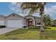 Tan house with white garage door, red door, and palm tree in front at 1347 Hedgewood Cir, North Port, FL 34288