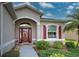 Front entrance with red door, arched windows, and landscaping at 1347 Hedgewood Cir, North Port, FL 34288