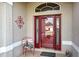 Red front door with glass panels and a decorative metal chair at 1347 Hedgewood Cir, North Port, FL 34288