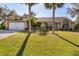 Single-story home with attached garage, palm trees, and well-manicured lawn at 14057 Maxwell Ave, Port Charlotte, FL 33953