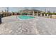 Community pool with brick pavers, covered seating, and building in background at 17565 Opal Sand Dr # 401, Venice, FL 34293