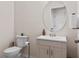 Bathroom with round mirror, white vanity, and toilet at 22116 Seaton Ave, Port Charlotte, FL 33954