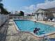 Community pool with children playing, surrounded by patio furniture and landscaping at 24667 Rio Villa Lakes Cir, Punta Gorda, FL 33950