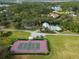 Scenic aerial of property with a tennis court, pool and cabana surrounded by lush greenery at 700 N River Rd, Venice, FL 34293