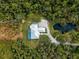 Aerial view of a home with a pool, pond, mature trees, and circular driveway at 700 N River Rd, Venice, FL 34293