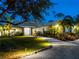 Elegant home exterior at night, featuring illuminated landscaping, a circular driveway, and pristine curb appeal at 700 N River Rd, Venice, FL 34293