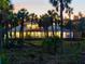 Stunning twilight view of home with screened lanai, balcony, and lush tropical surroundings, creating a private retreat at 700 N River Rd, Venice, FL 34293