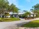 Beautiful home showcasing meticulous landscaping, a fountain, a circular driveway, and mature trees at 700 N River Rd, Venice, FL 34293