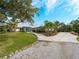 White house with metal roof, circular driveway, and tropical landscaping at 700 N River Rd, Venice, FL 34293