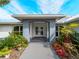 Elegant front entrance featuring a covered porch, double glass doors, decorative tile, and lush tropical landscaping for curb appeal at 700 N River Rd, Venice, FL 34293