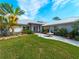 Beautifully landscaped front yard with green grass, mature palm trees, a central water fountain, and a concrete pathway at 700 N River Rd, Venice, FL 34293