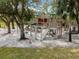 Outdoor playground with slides and climbing structure surrounded by shade trees and sandy ground at 700 N River Rd, Venice, FL 34293