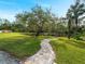 Scenic view of a serene pond with a stone path, lush greenery, and mature trees, perfect for a peaceful, natural setting at 700 N River Rd, Venice, FL 34293