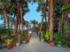 Charming wooden walkway adorned with potted plants, leading through lush tropical foliage and towering palm trees at 700 N River Rd, Venice, FL 34293