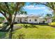 White two-story house with metal roof, landscaping, and large trees at 7563 Albert Tillinghast Dr, Sarasota, FL 34240