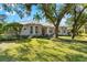 Two-story house with metal roof, lush landscaping, and mature trees at 7563 Albert Tillinghast Dr, Sarasota, FL 34240