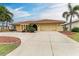 Tan single story home with terracotta tile roof, landscaping, and a large driveway at 820 Via Tunis, Punta Gorda, FL 33950