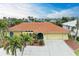 Tan single-story home with terracotta tile roof, palm trees, and a large driveway at 820 Via Tunis, Punta Gorda, FL 33950