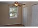 Cozy bedroom with ceiling fan, a window overlooking a green lawn, and a closet with white doors at 108 Pompano Se Dr # D, St Petersburg, FL 33705