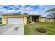Bright yellow house with red trim, two-car garage, and landscaped yard at 18204 Ackerman Ave, Port Charlotte, FL 33948
