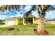 Bright yellow house with red trim, palm trees, and a well-manicured lawn at 18204 Ackerman Ave, Port Charlotte, FL 33948