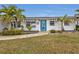 Front view of a charming home with a blue door, striped awnings and landscaping at 226 Spring Lake Nw Blvd, Port Charlotte, FL 33952