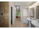 Hallway view of bright bathroom featuring dual sinks, tiled shower, and access to the bedroom at 4267 Adelaide Ave, North Port, FL 34288