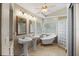 Bright bathroom features dual sinks, a soaking tub next to the window, and a glass block shower at 4267 Adelaide Ave, North Port, FL 34288