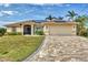 Tan house with solar panels, paver driveway, and landscaped lawn at 9214 Snapper Cir, Port Charlotte, FL 33981