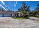 Tan house with red shutters and a two-car garage, surrounded by lush landscaping at 1447 Red Oak Ln, Port Charlotte, FL 33948