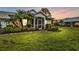 Evening view of a yellow house with a screened porch and lush landscaping at 2110 Royal Tern Cir, Punta Gorda, FL 33983