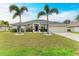 Single-story home with a landscaped lawn, palm trees, and a two-car garage at 2467 Odessa Ln, Punta Gorda, FL 33983