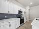 Modern kitchen featuring white cabinets, stainless steel appliances, and gray tile backsplash at 3733 Basket St, North Port, FL 34288