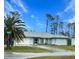 Light blue house with a gray roof, palm trees, and a driveway at 1022 Campbell St, Port Charlotte, FL 33953