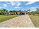 Tan house with three-car garage and paver driveway, surrounded by lush landscaping at 1041 Harbour Park Ct, Punta Gorda, FL 33983