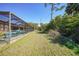 Screened-in pool area with teal chairs and grassy backyard at 18395 Edgewater Dr, Port Charlotte, FL 33948